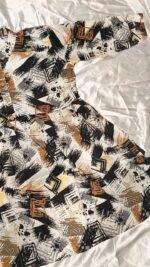 Woman wearing black, mustard and cream abstract printed flared midi dress with three-quarter sleeves.