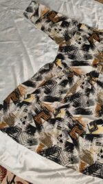Woman wearing black, mustard and cream abstract printed flared midi dress with three-quarter sleeves.